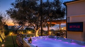 Un jacuzzi avec un logo Netflix, entouré d’arbres et doté de sièges extérieurs.