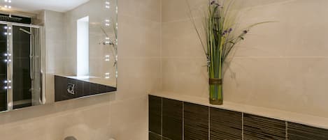 A bathroom with a white sink, a mirror, and a vase with flowers on the wall.