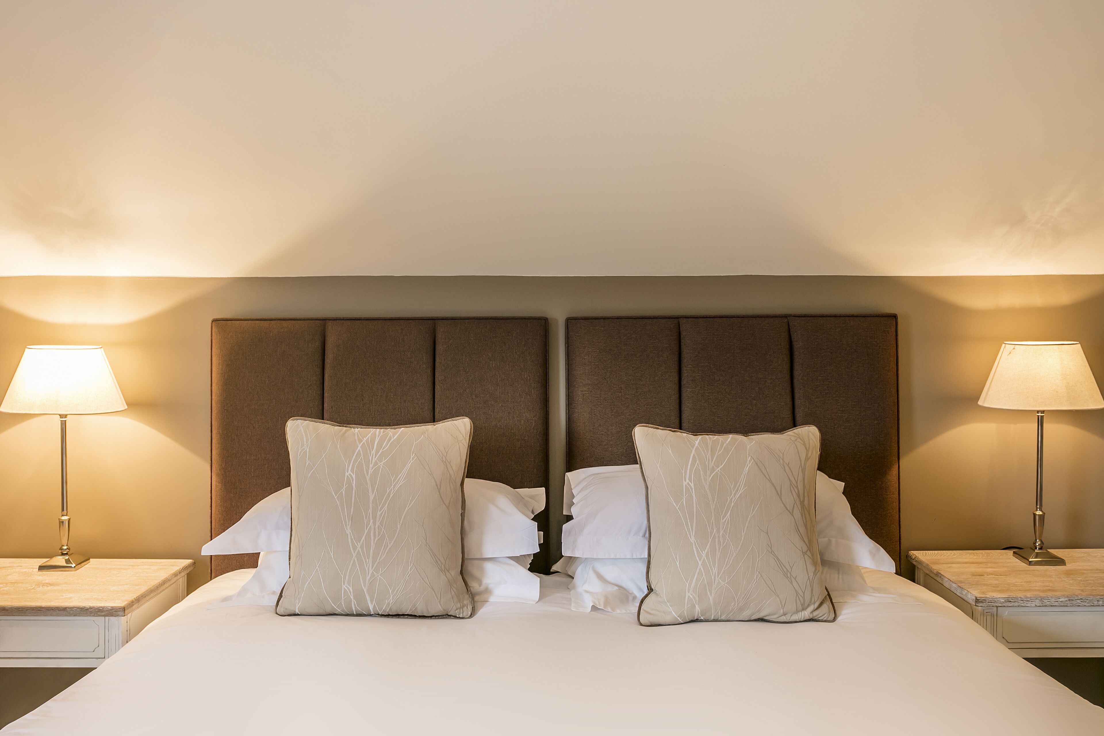 Una habitación de hotel con una cama grande, dos mesitas de noche y dos lámparas.