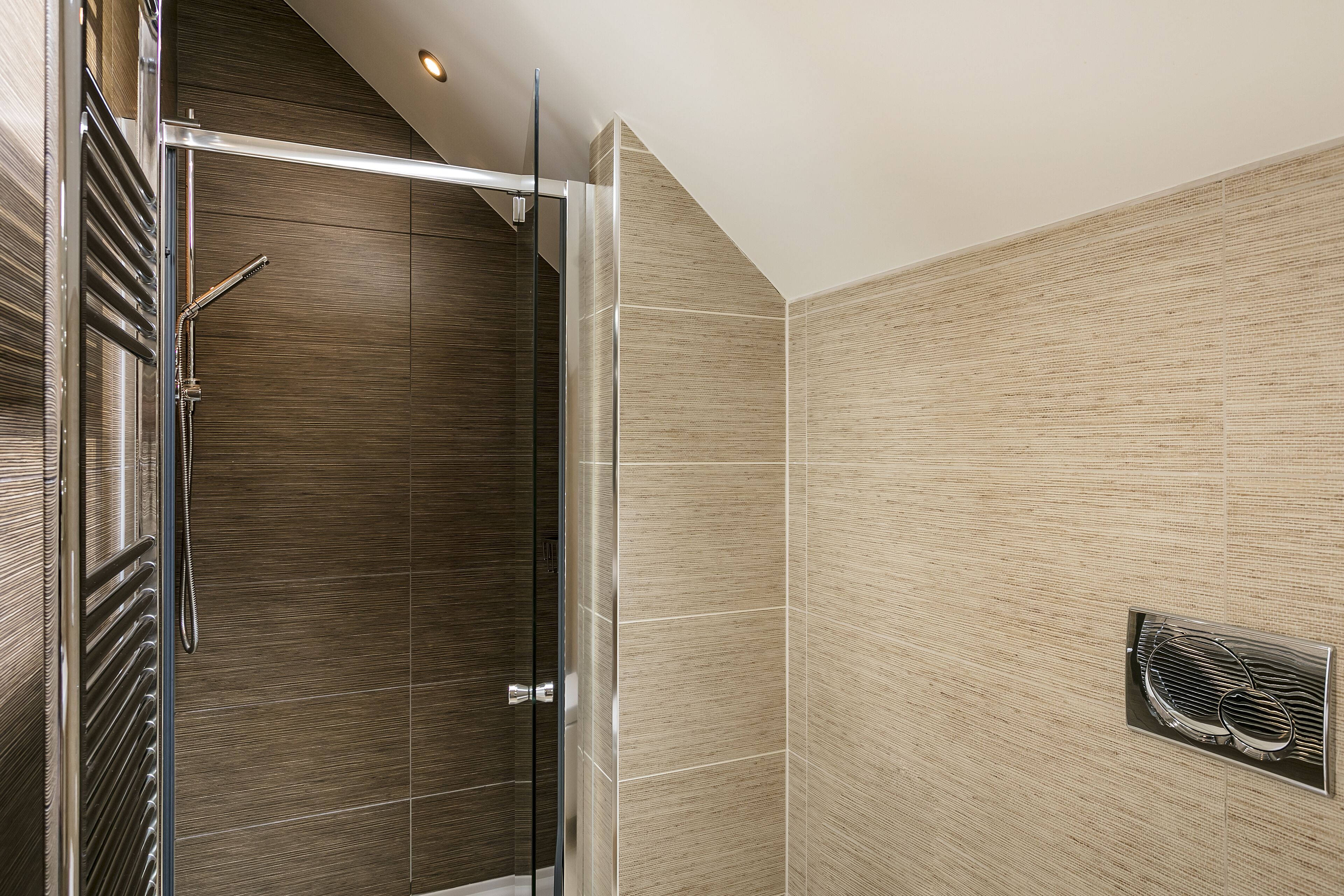 A modern bathroom with a glass shower enclosure, a built-in towel rack, and a ventilation system.