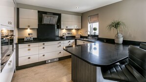 Une cuisine moderne dotée d’un îlot central, d’appareils électroménagers intégrés et d’une grande fenêtre.