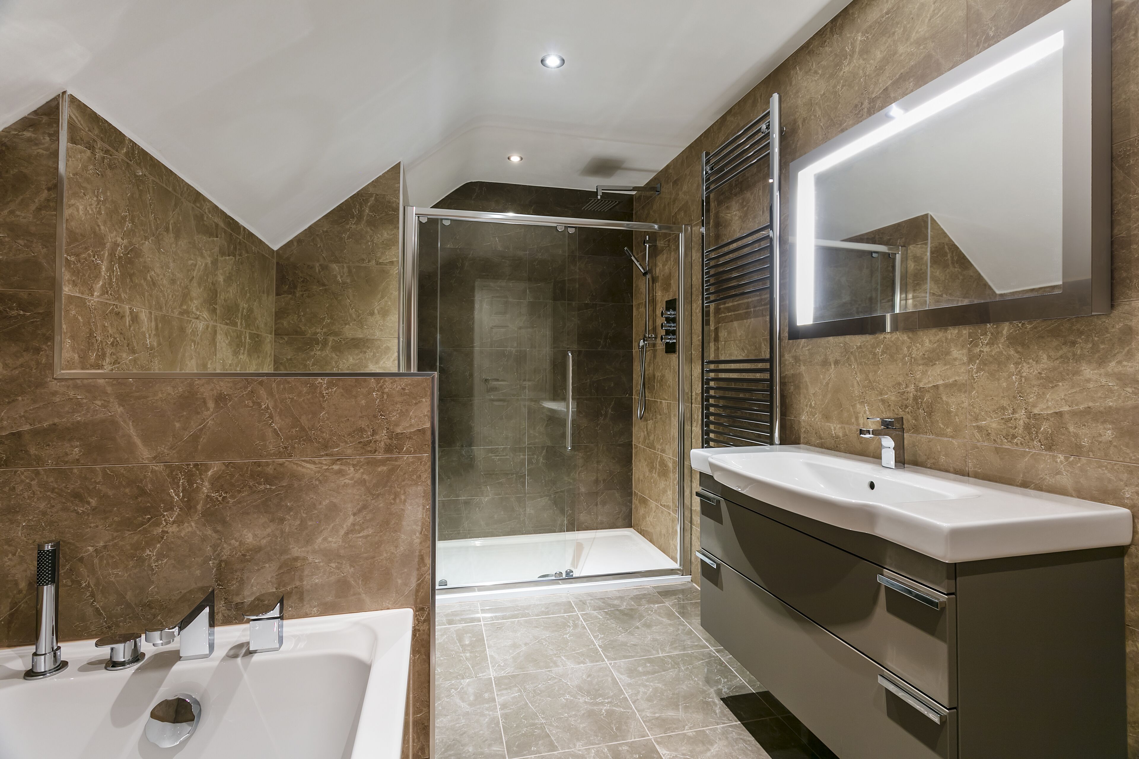 Une salle de bain moderne dotée d’une douche à parois de verre, d’une grande baignoire et d’un meuble-lavabo avec un miroir.