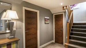 Un couloir avec deux portes en bois, une lampe et un tableau accroché au mur.