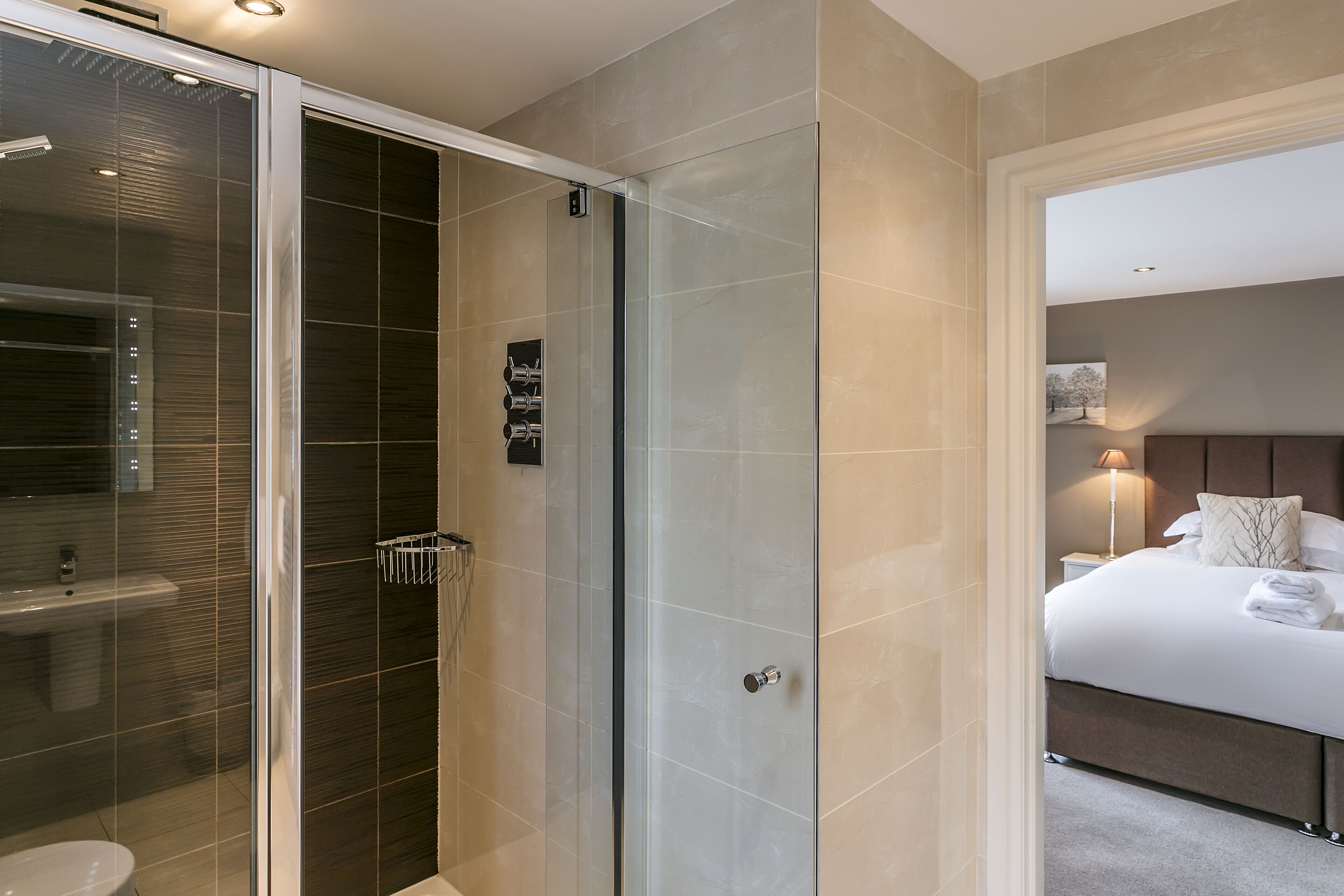 Ein modernes Badezimmer mit Duschkabine aus Glas, einer sichtbaren Toilette und einem separaten Waschbereich.