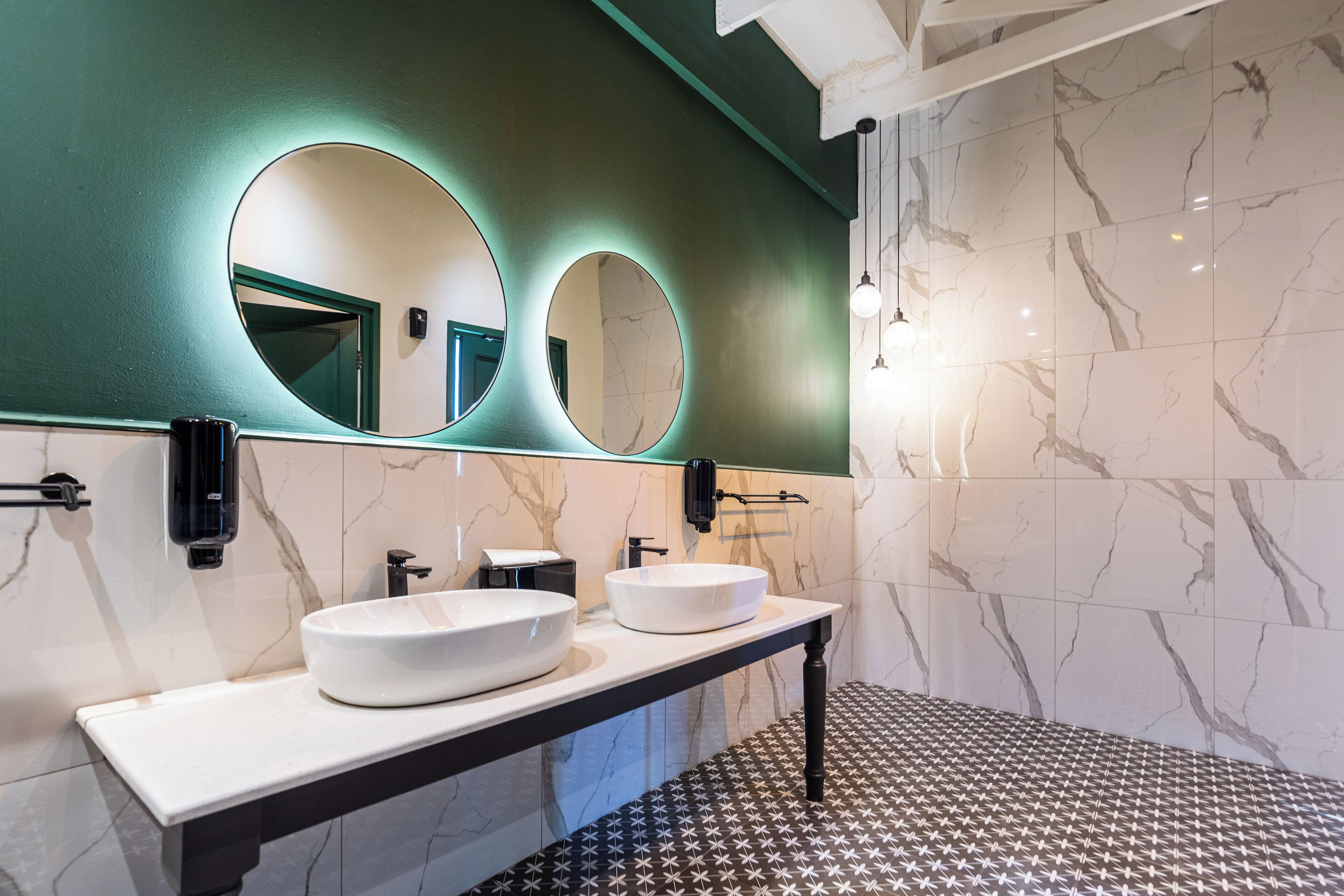 A modern bathroom with two sinks, a large mirror, and a patterned floor.