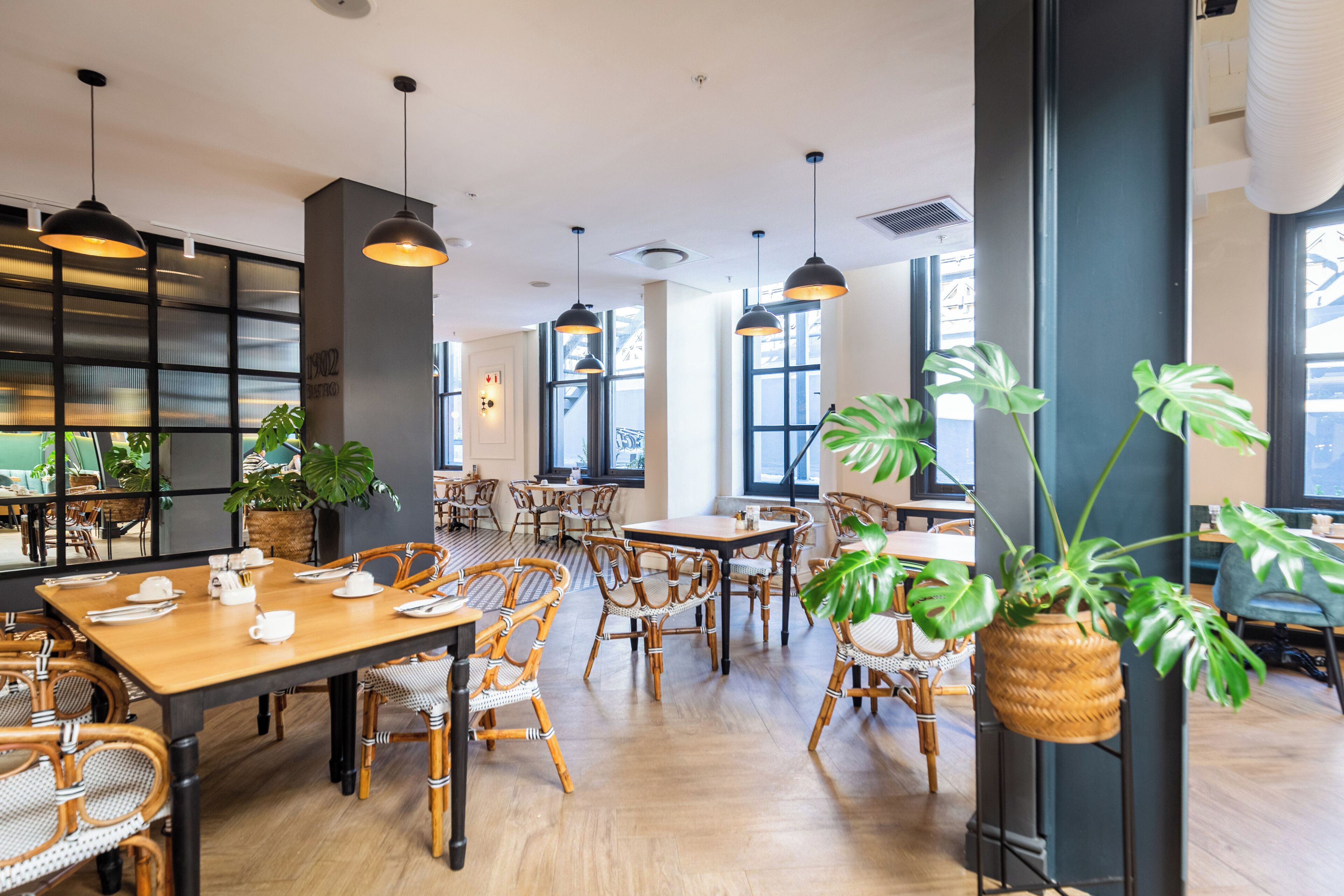 A spacious restaurant with high ceilings, large windows, and modern pendant lighting.