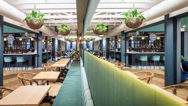 A modern restaurant with high ceilings, hanging plants, and a bar area. - Old Bank Hotel (Cape Town)