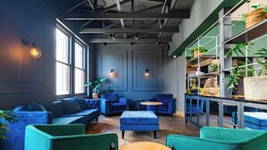 A modern lounge area with blue sofas, green armchairs, and wooden tables. - Old Bank Hotel (Cape Town)