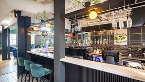 A bar area with a counter, bar stools, hanging light fixtures, and shelves with bottles and glasses. - Old Bank Hotel (Cape Town)