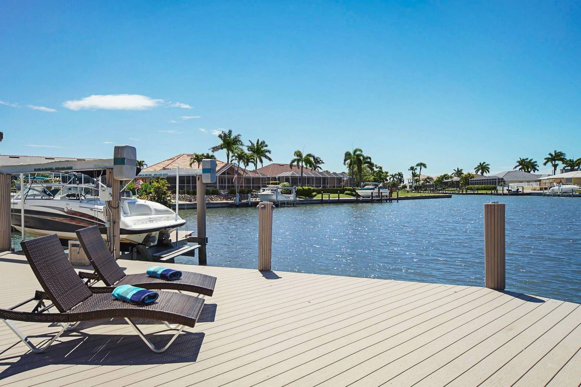 A wooden deck with lounge chairs and a marina in the background.