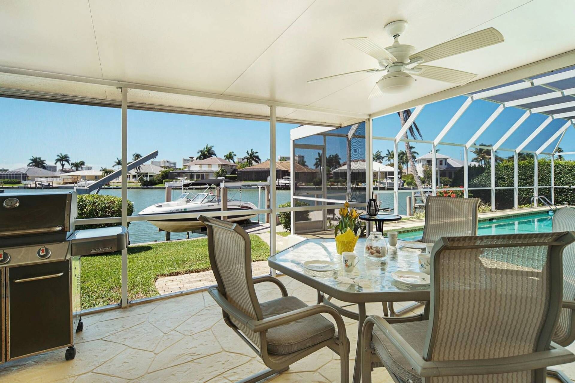 A covered outdoor area with a grill, seating, and a view of a body of water and buildings.