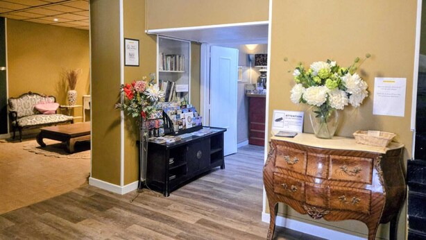 A reception area with a desk, a chair, a sofa, and a bookshelf. - Hôtel des Jacobines (Chalon-sur-Saone)