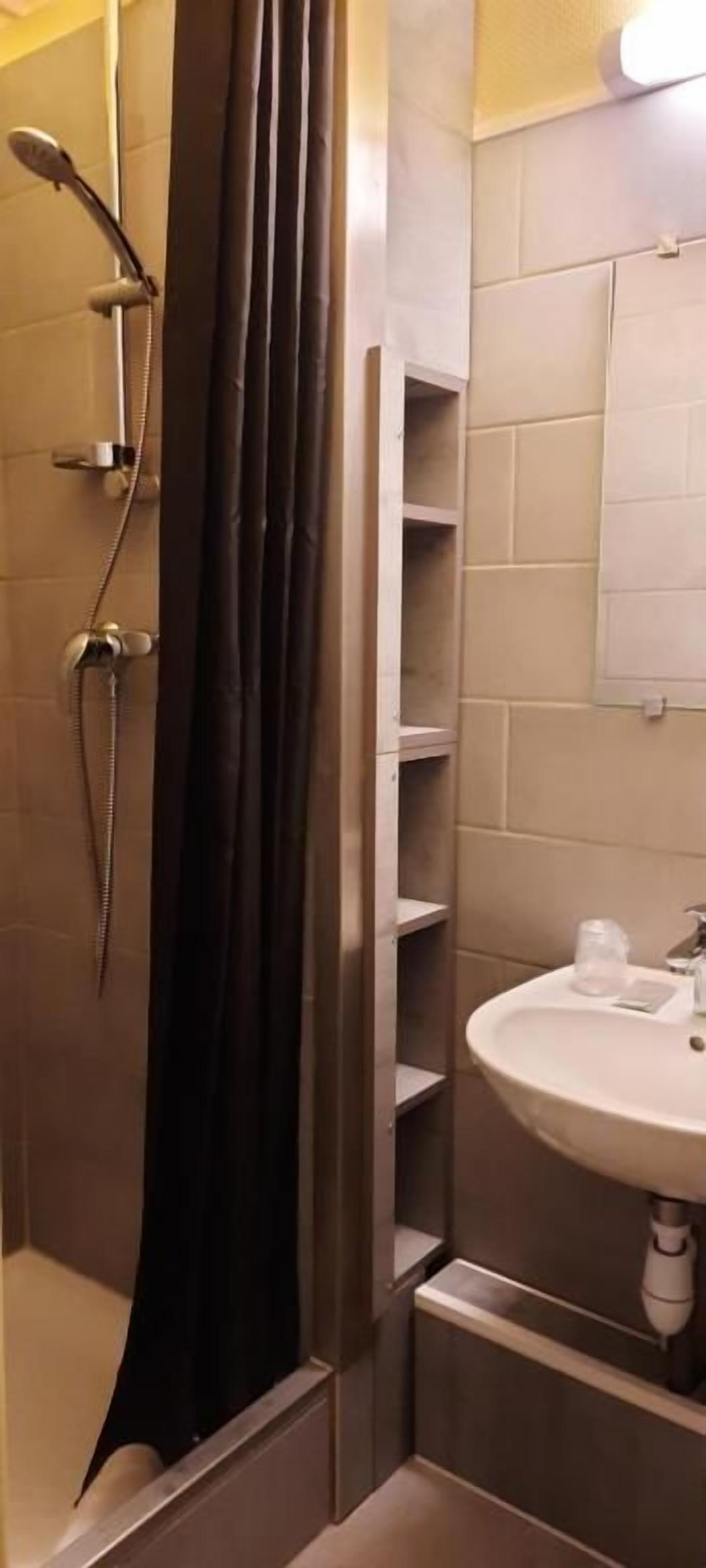 Un baño con ducha, lavamanos y espejo.