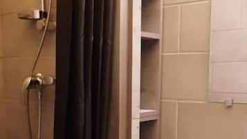 Un baño con ducha, lavamanos y espejo.