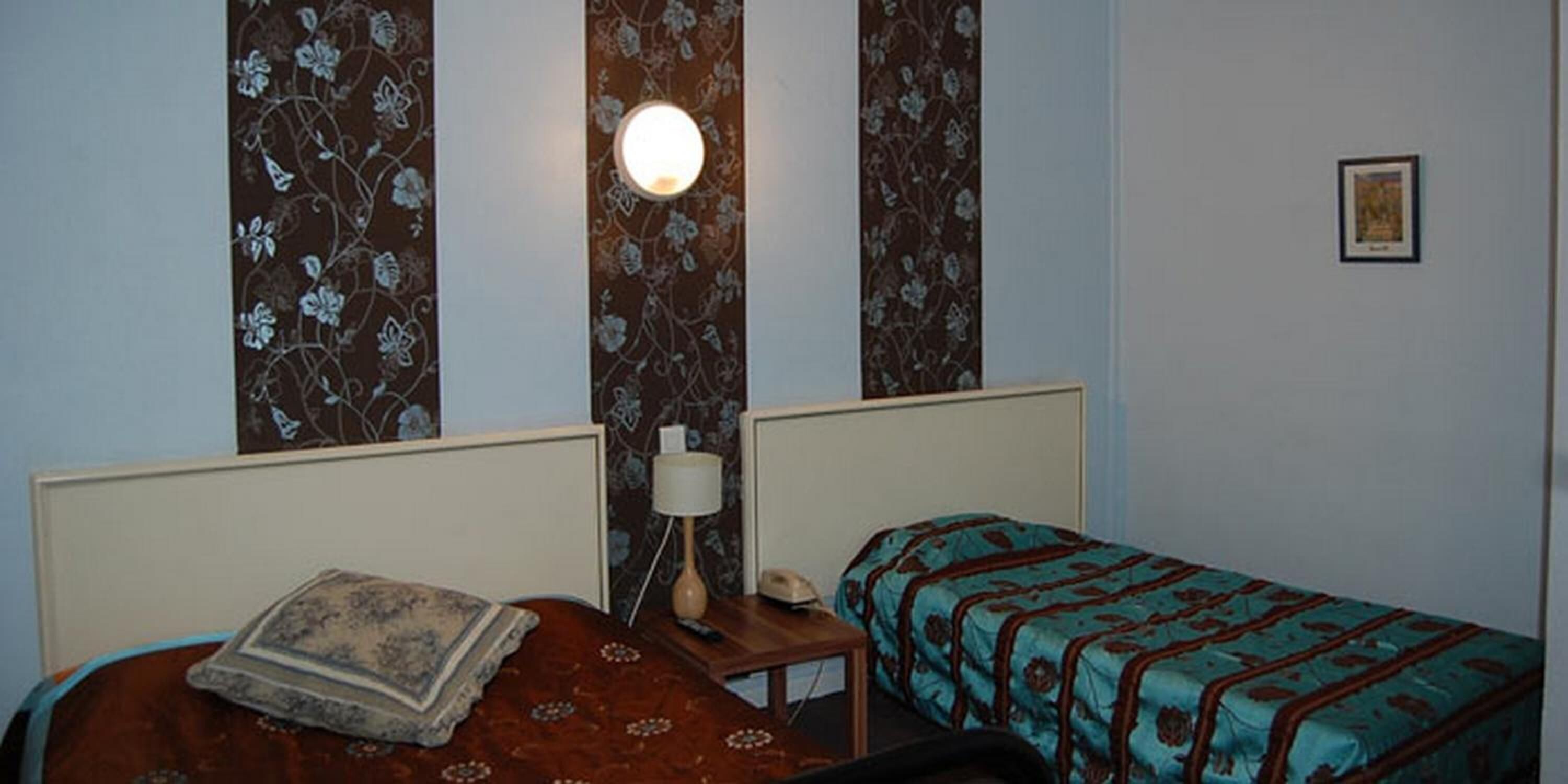 Un dormitorio con dos camas, una mesita de noche, una lámpara y una lámpara de pared.