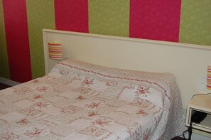 A bed with a floral-patterned bedspread in a room with striped wallpaper. - Hôtel des Jacobines (Chalon-sur-Saone)
