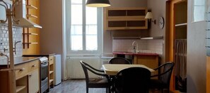 A compact kitchen with a dining area, a window providing natural light, and a built-in oven. - Hôtel des Jacobines (Chalon-sur-Saone)