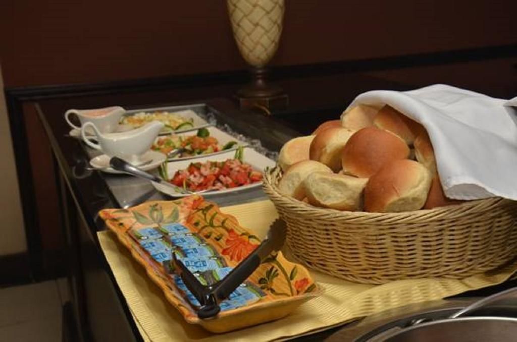 Un bufé de desayuno con pan, una cesta de frutas y una estación de café.