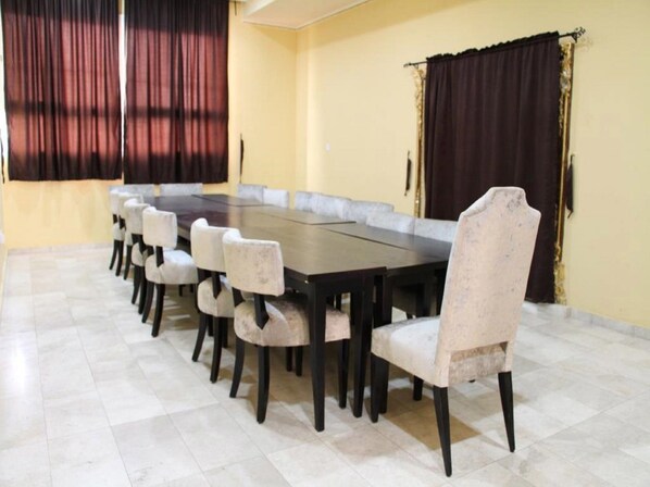 A conference room with a long table and chairs, large windows with curtains, and a tiled floor. - Golden Olive Resort (Umuahia)