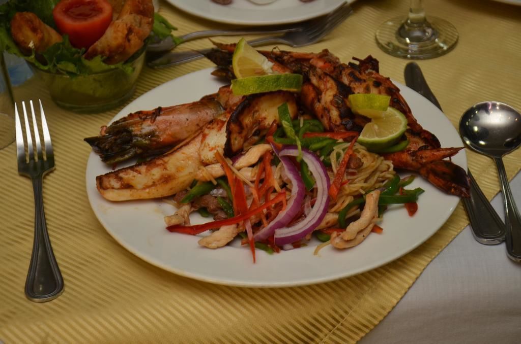 A plate of grilled chicken with vegetables and lime on a table.