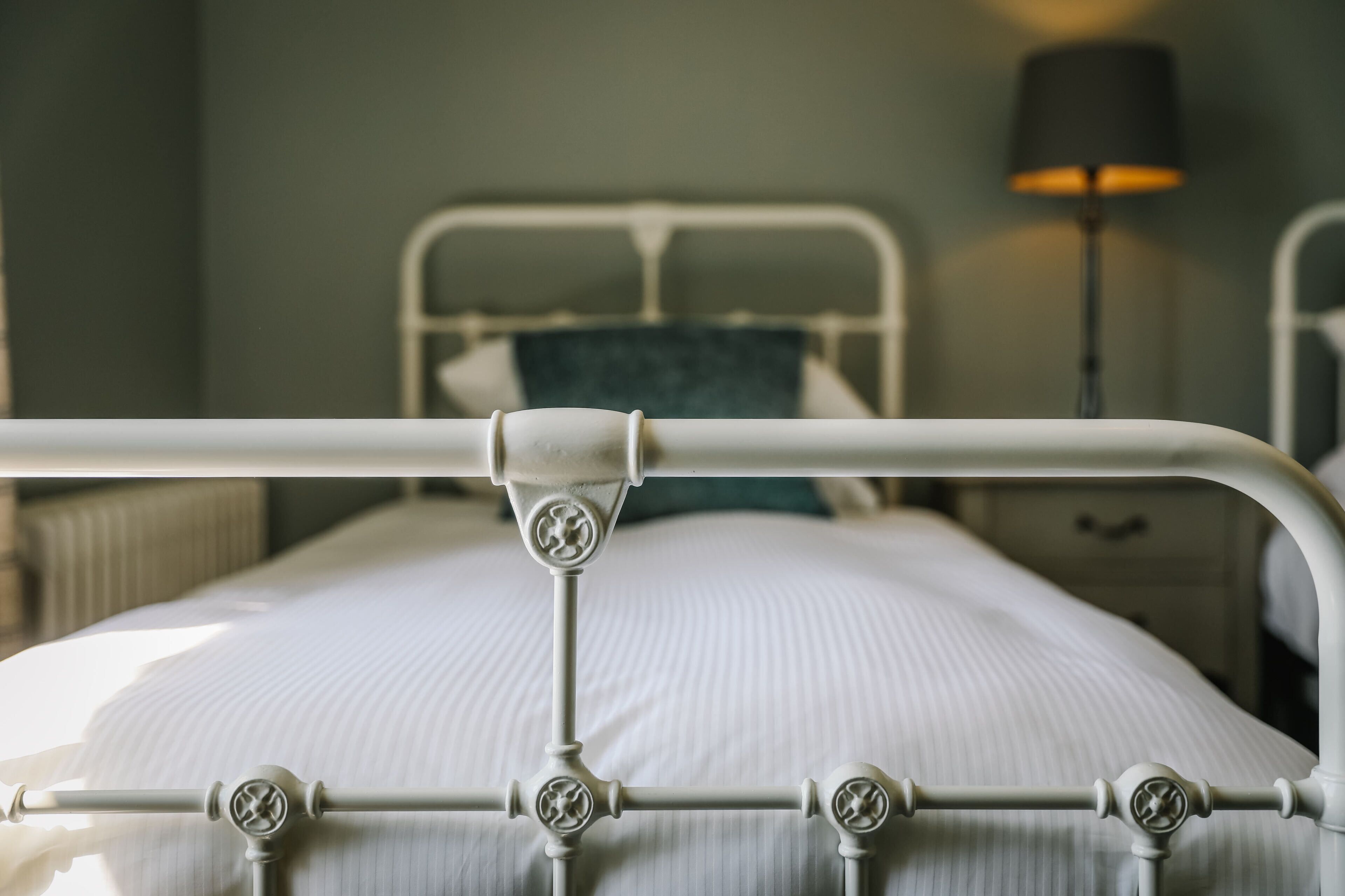 A bed with a metal frame and a headboard, a bedside lamp, and a nightstand with a drawer.