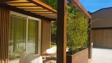 A modern outdoor patio with a pergola, seating area, and a planter with greenery.
