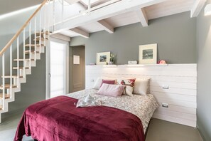 A bedroom with a bed, a staircase, and a white headboard.