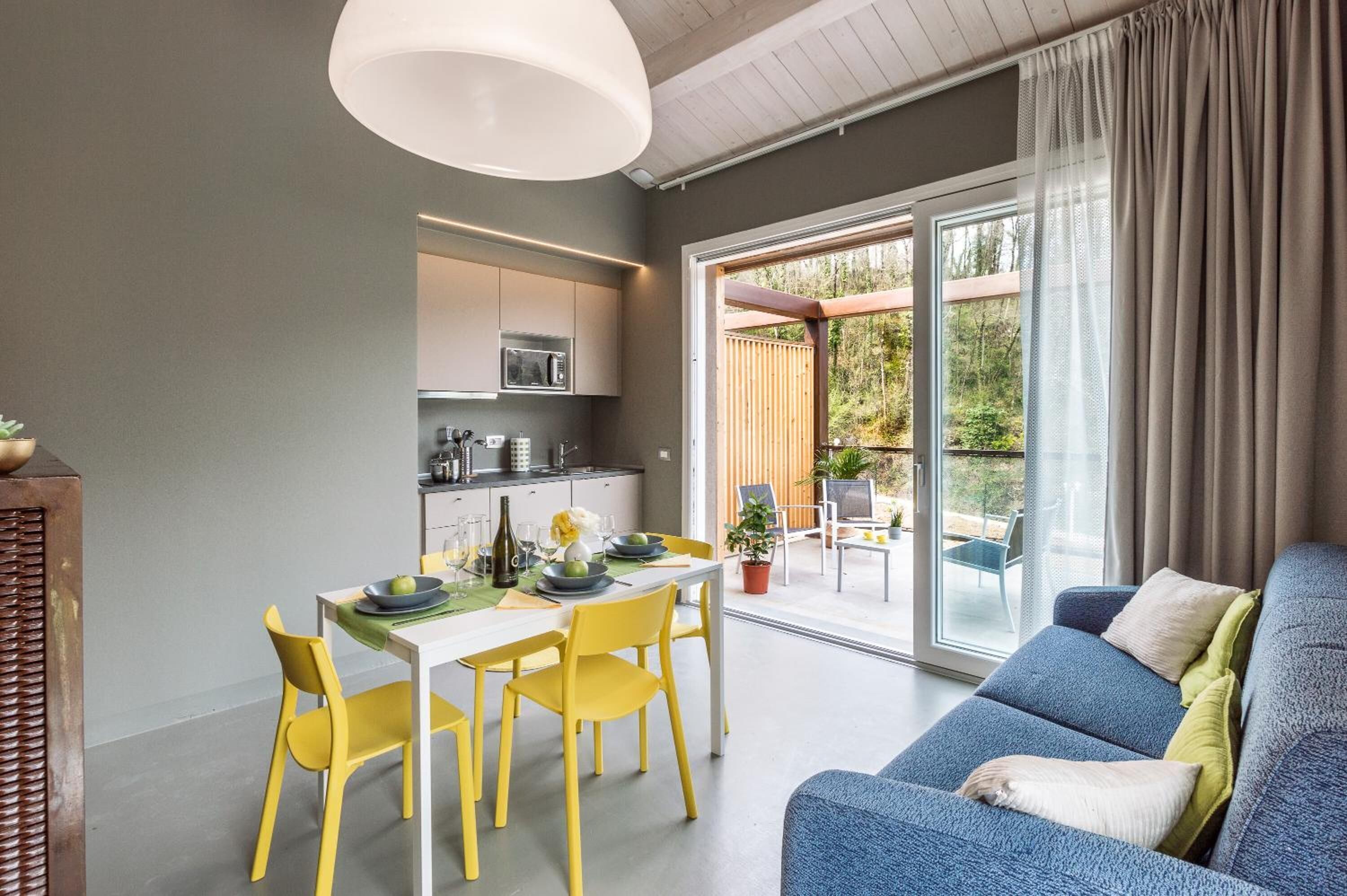 Una cucina moderna con mobili bianchi e un'area pranzo con sedie gialle.