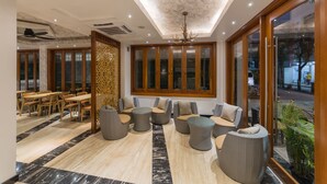 A modern lobby with a ceiling fan, seating area with sofas and chairs, and a view through large windows. - Samann Host (Hulhumalé)