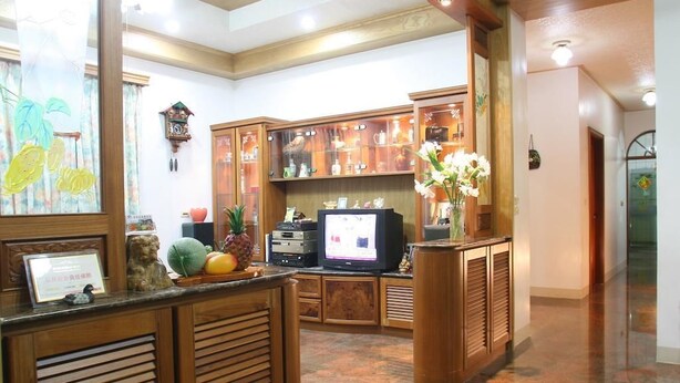 A reception area with wooden cabinets, a television, and a decorative plant. - Yilan Feeling Homestay B&B (Wujie)