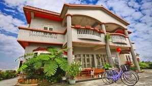 A two-story house with a balcony, potted plants, and a bicycle. - Yilan Feeling Homestay B&B (Wujie)
