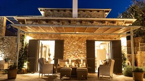 Ein Terrassenbereich im Freien mit Steinmauern, Holzmöbeln und einer Pergola.