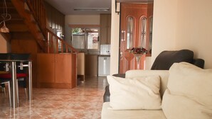 Ein geräumiger Wohnbereich mit einer Couch, einem Esstisch mit Stühlen und einer Küche im Hintergrund.
