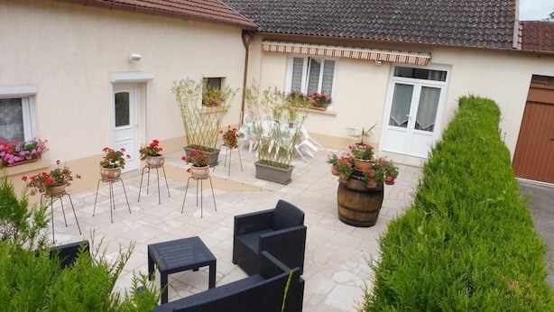 Une cour avec des espaces de repos en plein air, des plantes en pot et un toit recouvert de tuiles.