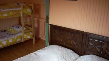 A room with bunk beds, a wooden headboard, a radiator, and a small picture on the wall.