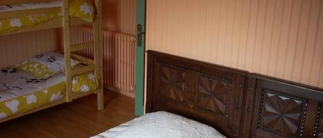 A room with bunk beds, a wooden headboard, a radiator, and a small picture on the wall.