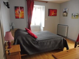 Un dormitorio con cama, mesita de noche, lámpara, ventana con cortinas y decoración en la pared.