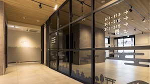 A modern hotel lobby with glass partitions, numbered room signs, and a cityscape silhouette on the floor. - M’s Hotel Sanjo Omiya (Kyoto)