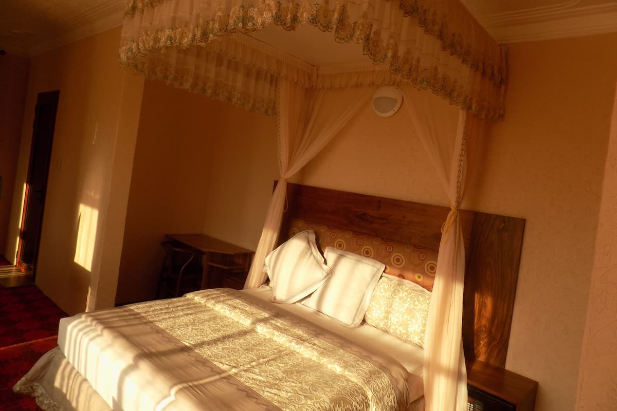 A four-poster canopy bed with a wooden headboard, a bedside table, and a nightstand.