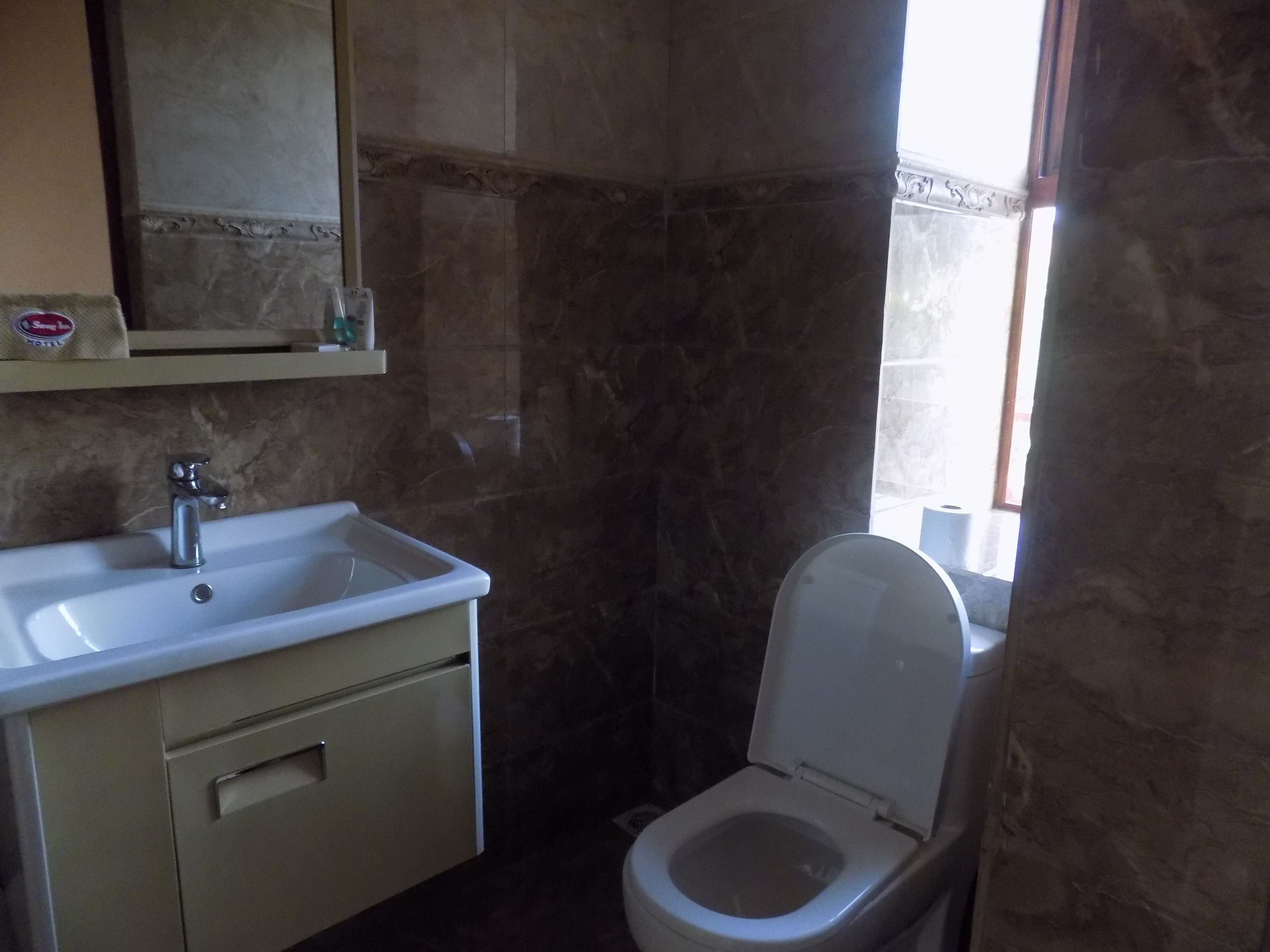 Un baño con un lavamanos blanco, un espejo y un inodoro.