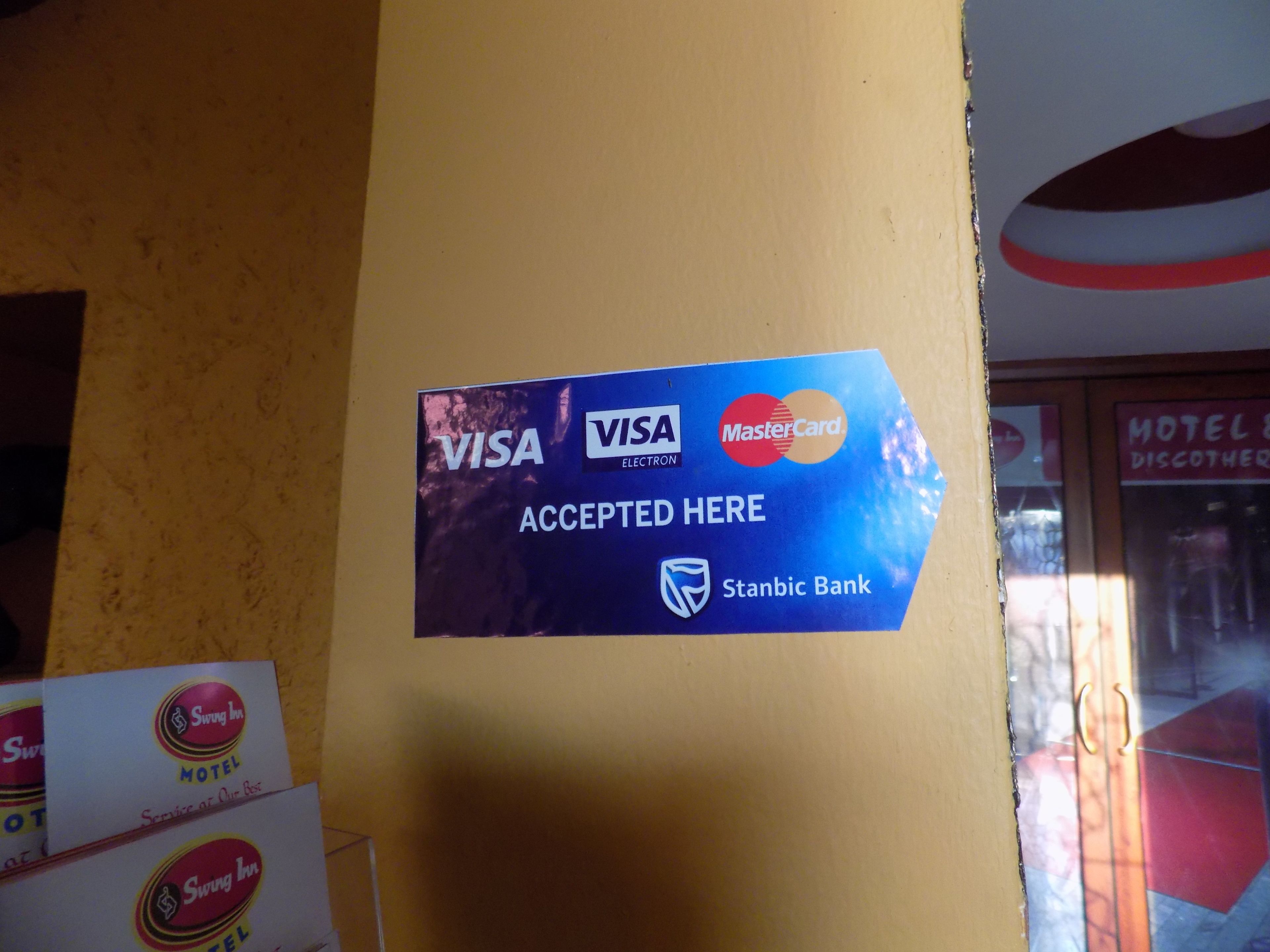 Eine Wand mit einem Schild, das die Annahme von VISA, MasterCard und MasterCard mit dem Stanbic Bank Logo anzeigt.
