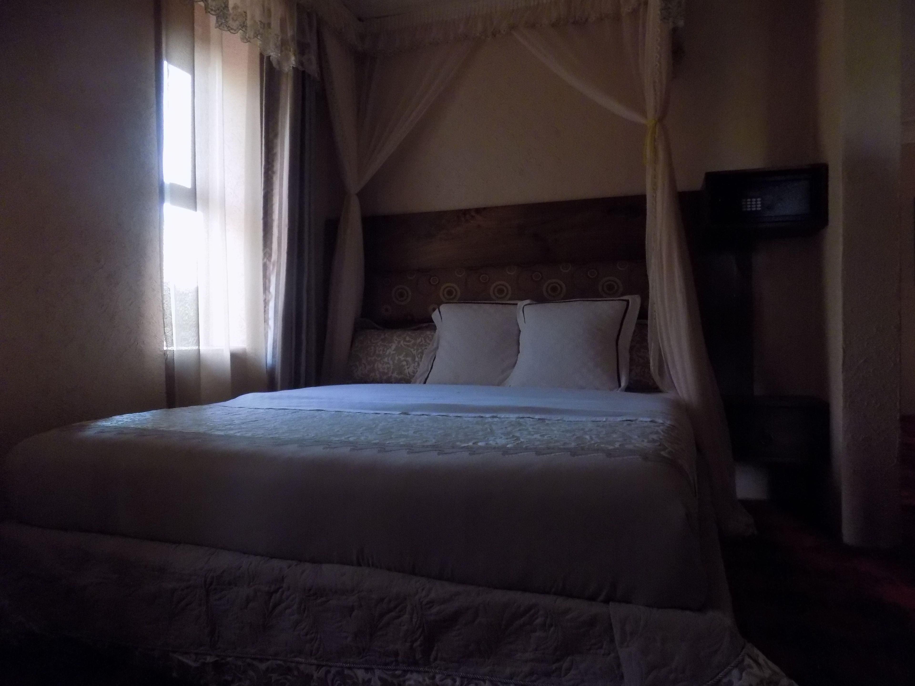 Una cama con dosel, una mesita de noche y un televisor montado en la pared.