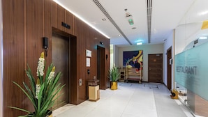 A modern hotel lobby with wooden paneling, a reception desk, and a glass wall advertising a restaurant. - Le Wana Hotel (Dubai)