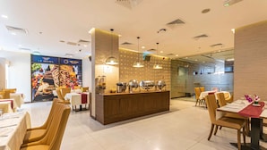 A modern restaurant with a central buffet area, multiple dining tables, and chairs. - Le Wana Hotel (Dubai)