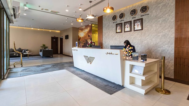 A reception area with a modern design, featuring a reception desk, wall-mounted clocks, and framed pictures. - Le Wana Hotel (Dubai)