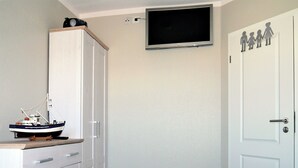A bedroom with a bed, a wardrobe, a television mounted on the wall, and a small ship model on the dresser. - Centrally located apartment close to the beach for max. 4 pers. with terrace, WLAN, washing machine (Ostseebad Prerow)