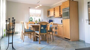 A modern kitchen with wooden cabinets, a dining table with chairs, and a built-in oven. - Centrally located apartment close to the beach for max. 4 pers. with terrace, WLAN, washing machine (Ostseebad Prerow)