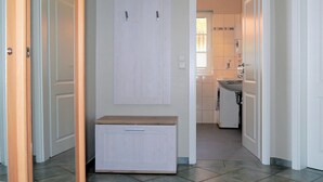 A hallway with a white wardrobe, a wooden bench, and a kitchen area with a sink and cabinets. - Centrally located apartment close to the beach for max. 4 pers. with terrace, WLAN, washing machine (Ostseebad Prerow)