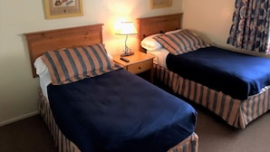A hotel room with two single beds, a nightstand with a lamp, and two framed pictures on the wall. - Cozy Condo in Chandler, entire unit to yourself with balcony in gated community. (Chandler)