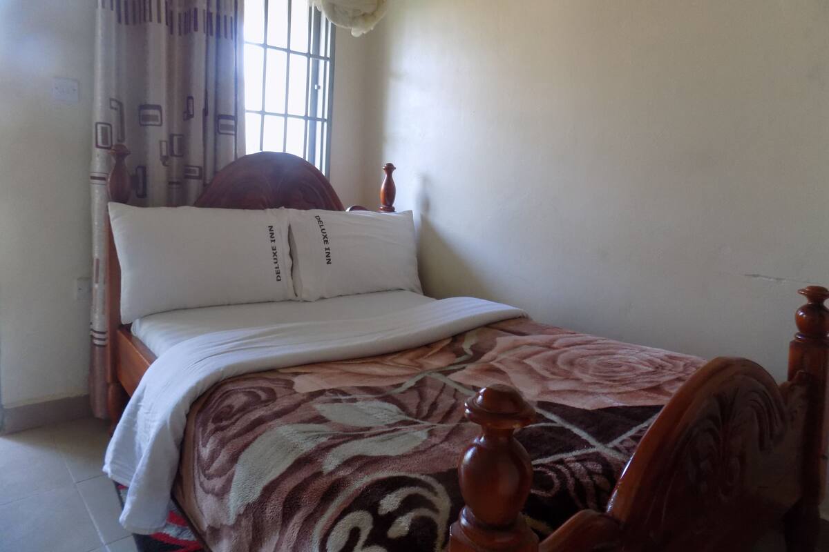 Uma cama com cabeceira, duas almofadas e um cobertor.
